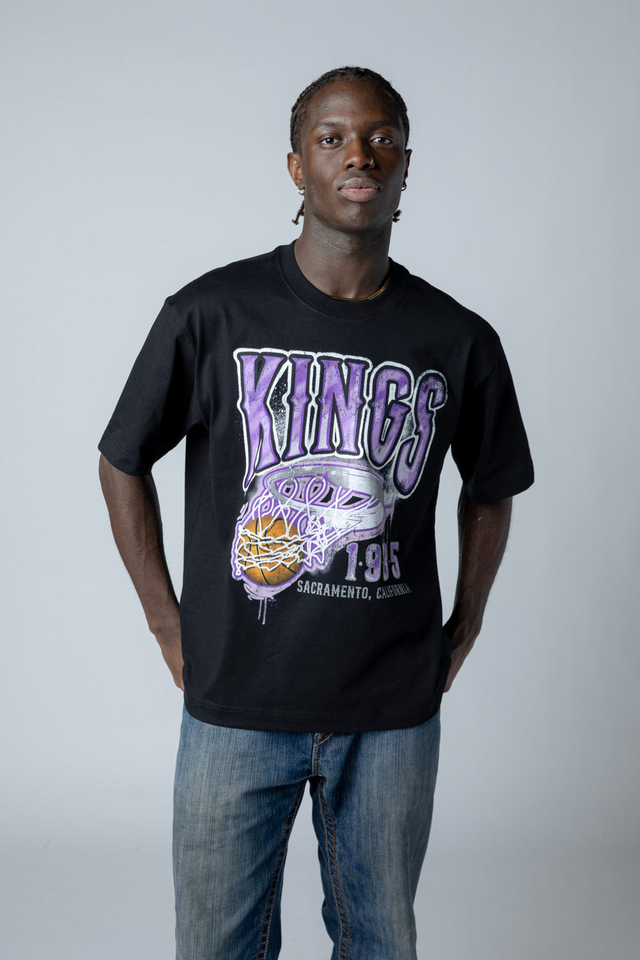 Person wearing a black 'KINGS' t-shirt with a graphic design on a plain background